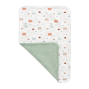 May include: A soft, reversible baby blanket with a white side featuring a geometric pattern in orange, red, pink, and grey. The other side is a solid light green.