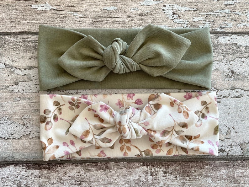 May include: Two knotted headbands, one solid sage green and one with a white background and a brown and pink floral pattern.