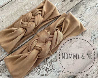 May include: Two brown knotted headbands, made of soft fabric, with the text "Mommy & Me" in a speech bubble.