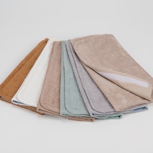 K&ouml;nnte beinhalten: Ein Set aus sieben saugf&auml;higen Wickelunterlagen in verschiedenen Farben, darunter Braun, Wei&szlig;, Beige, Blau und Grau. Die Unterlagen bestehen aus weichem, pl&uuml;schem Stoff und haben eine wasserdichte R&uuml;ckseite.