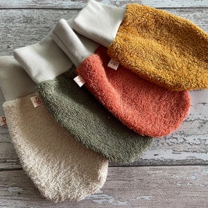 May include: Four different colored terrycloth hand mitts with white cuffs. The mitts are beige, green, orange, and yellow. Each mitt has a small white tag with a letter "B" on it.