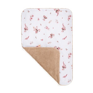 May include: A white baby blanket with a floral pattern on one side and a soft, brown, fuzzy texture on the other side.