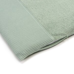 May include: A sage green bath mat with a waffle texture on one side and a soft, plush texture on the other side.