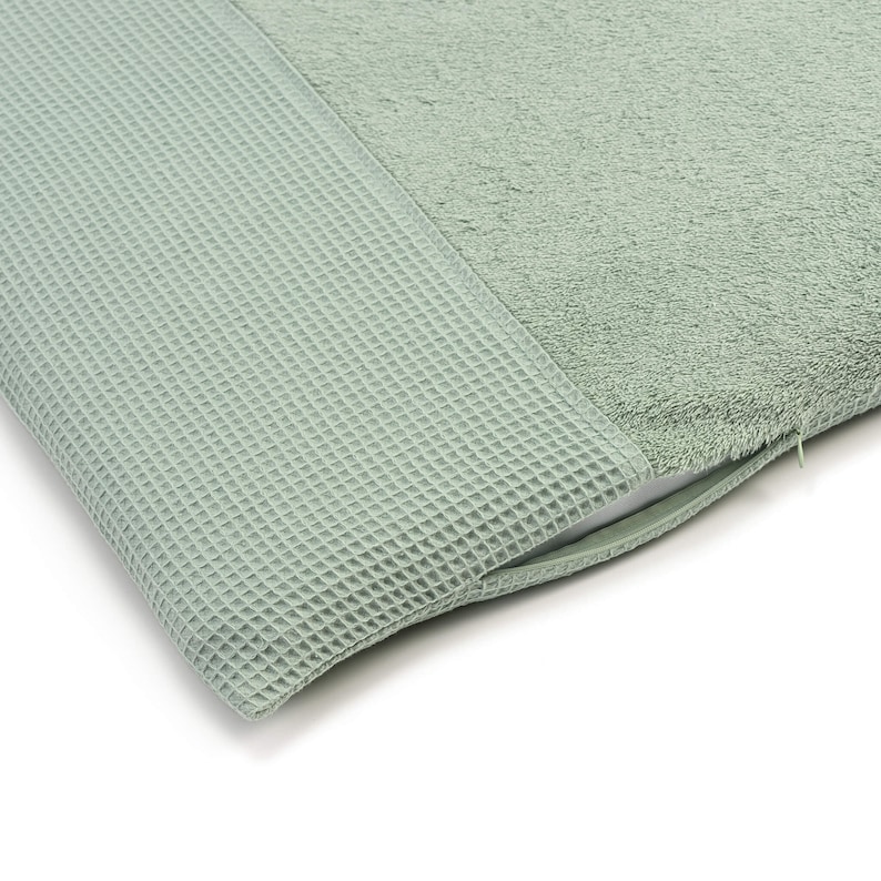 May include: A sage green bath mat with a waffle texture on one side and a soft, plush texture on the other side.