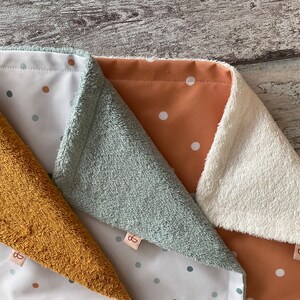 May include: Three fabric baby blankets with different colored borders and white polka dots on a white background. The blankets are made of soft, plush fabric and are perfect for cuddling.
