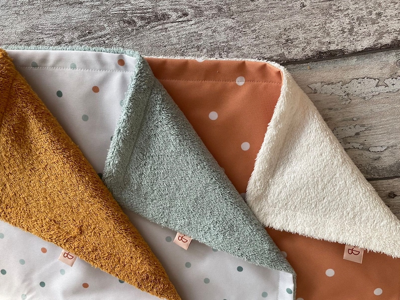 May include: Three fabric baby blankets with different colored borders and white polka dots on a white background. The blankets are made of soft, plush fabric and are perfect for cuddling.
