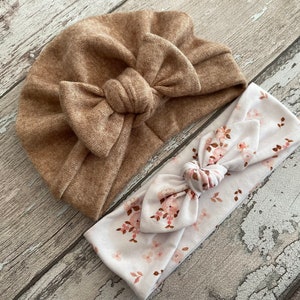 Könnte beinhalten: Ein braunes Turban-Stirnband mit einer großen Schleife und ein weißes Stirnband mit Blumenmuster.