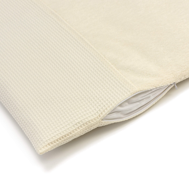 May include: A cream-colored pillow with a waffle-textured side and a soft, fuzzy side. The pillow has a zipper closure.