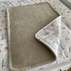 K&ouml;nnte beinhalten: Ein beiger Wickelauflagenbezug mit wei&szlig;em Blumenmuster. Der Bezug ist aus weichem, saugf&auml;higem Material gefertigt und sch&uuml;tzt Ihre Wickelauflage perfekt vor Versch&uuml;ttungen und Flecken.
