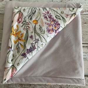 May include: A gray and white floral patterned blanket with a soft, textured surface. The blanket is folded in half, revealing the floral pattern.