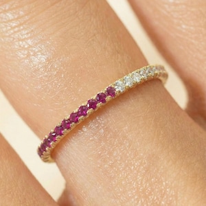 May include: A thin gold band ring featuring a row of alternating small round gemstones. The design includes a section of vibrant pink rubies followed by a section of clear white diamonds, set in a continuous pavé style along the metal band.