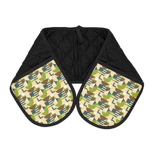 Può includere: Doppio guanto da forno trapuntato nero con un motivo geometrico verde, marrone e blu su sfondo crema. Il guanto ha un anello per appenderlo ed è progettato per proteggere le mani dal calore.