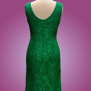 Puede incluir: Un vestido verde esmeralda sin mangas con estampado de rosas. El vestido tiene una silueta ajustada y una cremallera en la espalda.