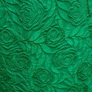 Puede incluir: Tela verde con un patr&oacute;n en relieve de rosas. La tela tiene un aspecto texturizado, casi en 3D.