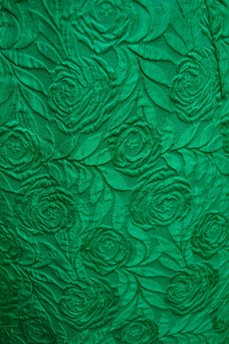 Puede incluir: Tela verde con un patr&oacute;n en relieve de rosas. La tela tiene un aspecto texturizado, casi en 3D.