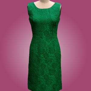 Puede incluir: Un vestido verde sin mangas con estampado floral. El vestido es entallado y tiene un escote recto.