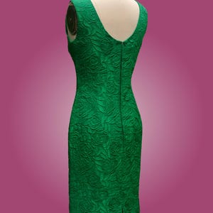 Puede incluir: Un vestido verde esmeralda sin mangas con un patr&oacute;n floral en relieve. El vestido tiene un escote en V y una cremallera en la espalda.