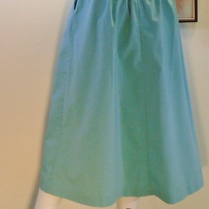 May include: A light blue midi skirt with a gathered waistband and pockets on the sides.