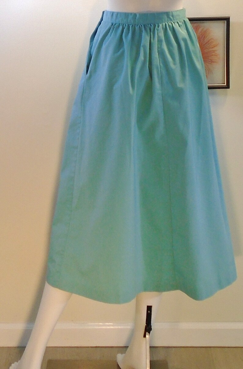 May include: A light blue midi skirt with a gathered waistband and pockets on the sides.