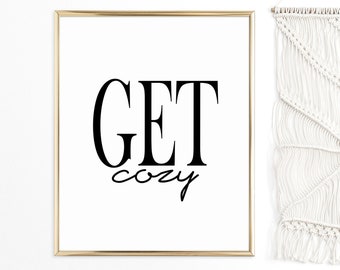 May include: A gold framed print with the text "GET cozy" in black lettering on a white background.
