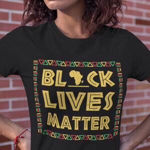 Powerful black T-shirt featuring "BLACK LIVES MATTER" in bold gold lettering with a silhouette of Africa, framed by a vibrant Pan-African patterned border, ideal for social justice advocates and supporters of equality and civil rights.