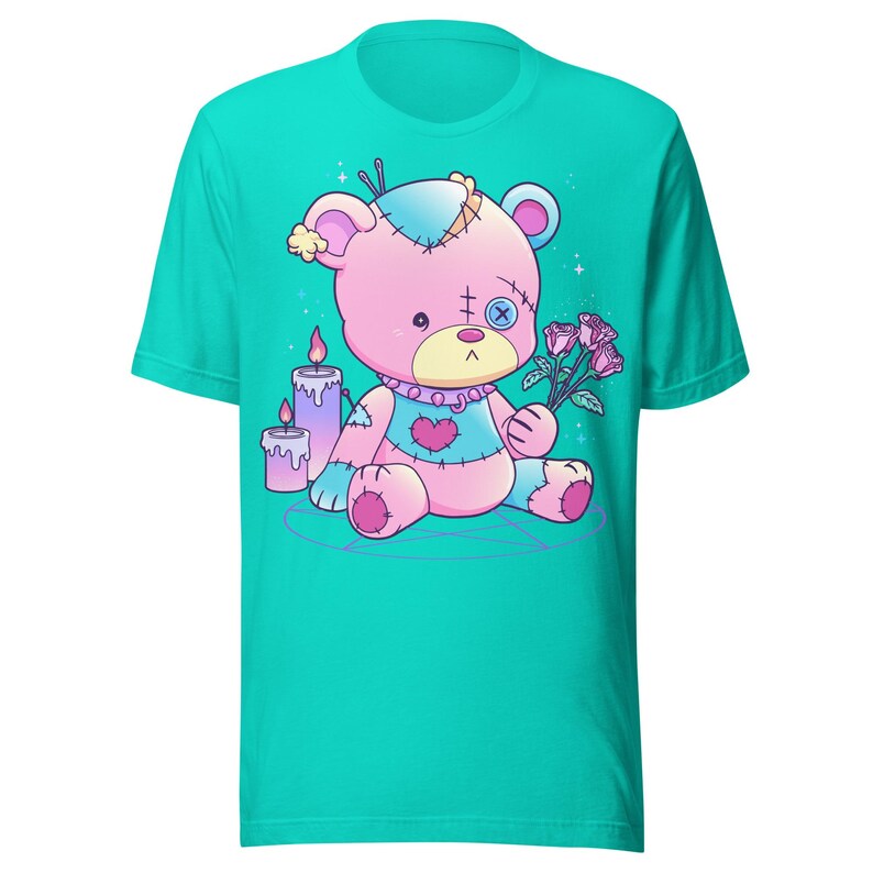 May include: A turquoise t-shirt with a pink and white stitched teddy bear holding a bouquet of pink roses. The teddy bear is sitting on a purple pentagram with two purple candles.