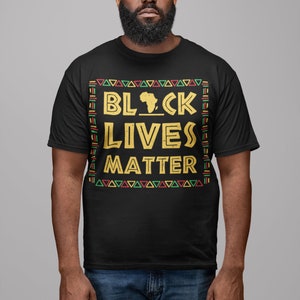 Peut inclure: Un t-shirt noir avec un motif dor&eacute; qui dit "Black Lives Matter" avec un contour du continent africain. Le motif est entour&eacute; d'un motif color&eacute; de triangles et de lignes.