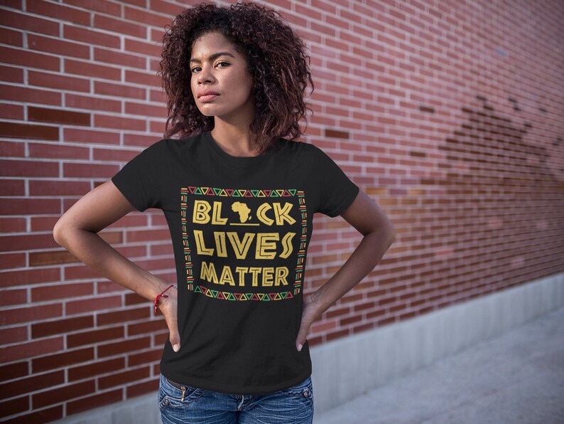 Powerful black T-shirt featuring "BLACK LIVES MATTER" in bold gold lettering with a silhouette of Africa, framed by a vibrant Pan-African patterned border, ideal for social justice advocates and supporters of equality and civil rights.