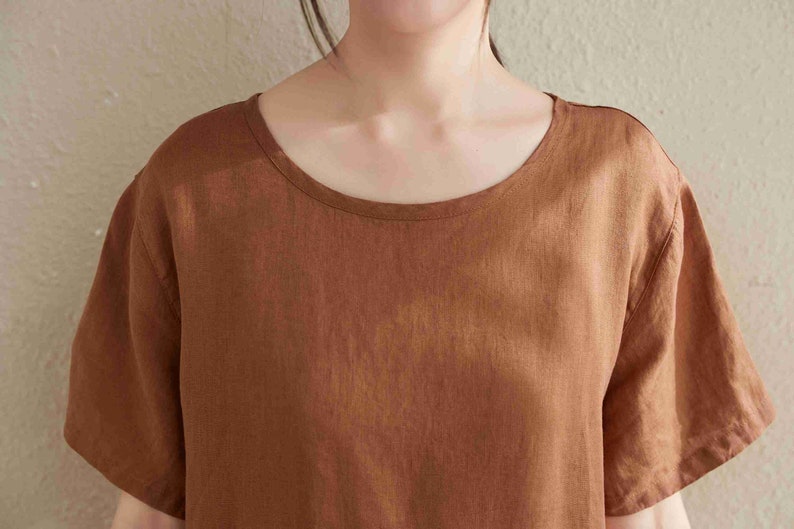Puede incluir: Una camisa de lino marr&oacute;n de manga corta con cuello redondo.