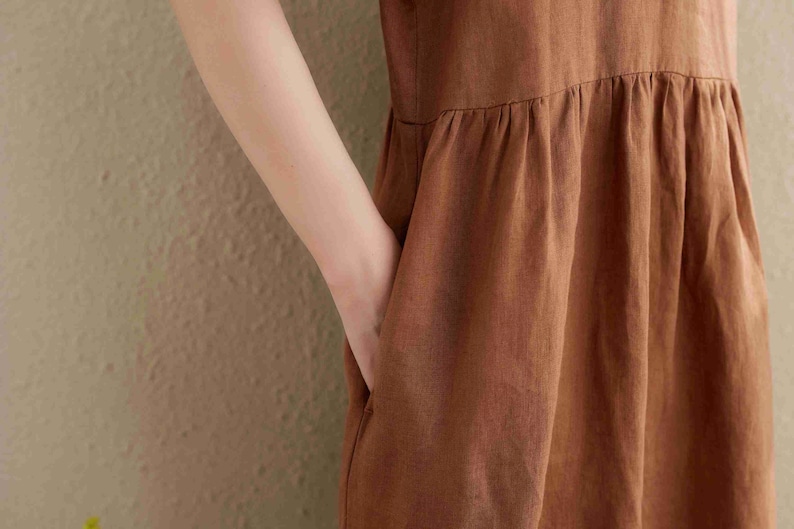 Puede incluir: Un vestido de lino marr&oacute;n con falda fruncida y un dise&ntilde;o sencillo y sin mangas.