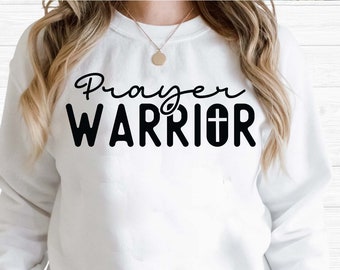 May include: A white sweatshirt with the text "Prayer Warrior" in black lettering. The word "Prayer" is in a cursive font and the word "Warrior" is in a bold, block font. A small cross is included in the word "Warrior".