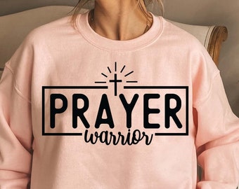May include: Pink sweatshirt with a black graphic that says "PRAYER warrior" with a cross and sunburst above the text.