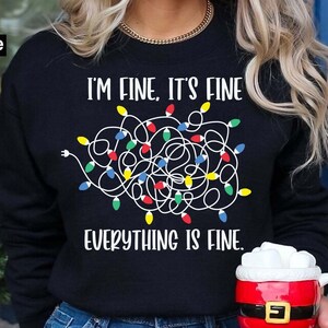 May include: Black sweatshirt with a white graphic of tangled Christmas lights and the text "I'm fine, it's fine, everything is fine."