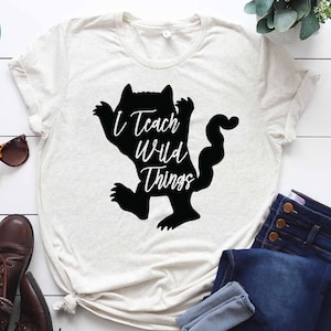 May include: A white t-shirt with a black silhouette of a wild thing with the text "I Teach Wild Things" on it.