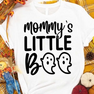 May include: White t-shirt with black text that reads "Mommy's Little Boo" with two ghost illustrations.
