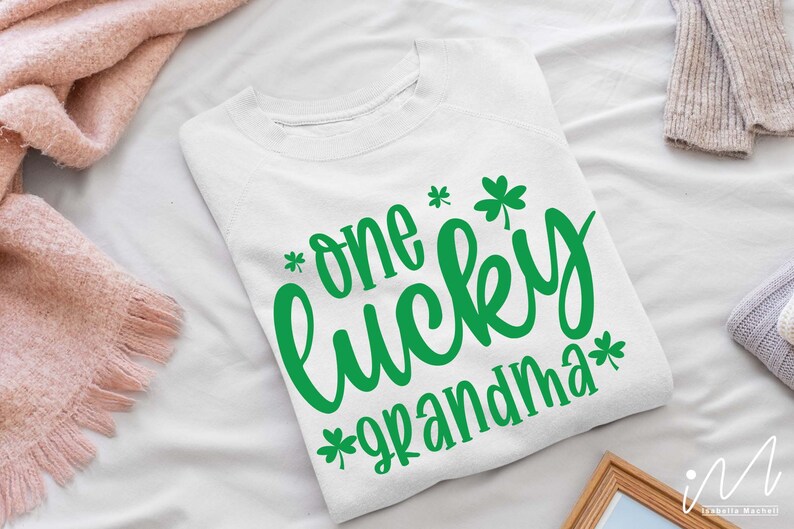 K&ouml;nnte beinhalten: Wei&szlig;er Pullover mit gr&uuml;nen Kleeblatt-Designs und dem Text "*one lucky grandma*"