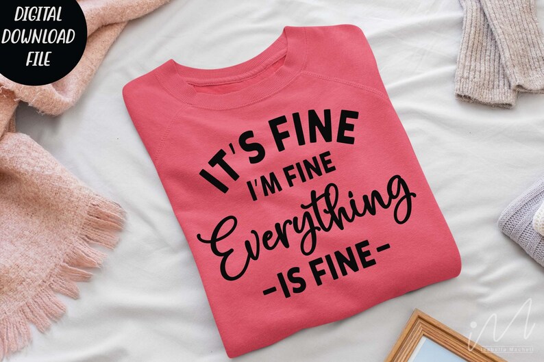 May include: A coral-colored crewneck sweatshirt featuring black text that reads IT'S FINE I'M FINE Everything -IS FINE- in a mix of bold sans-serif and cursive fonts. The garment is folded and displayed flat, showcasing the front graphic design.