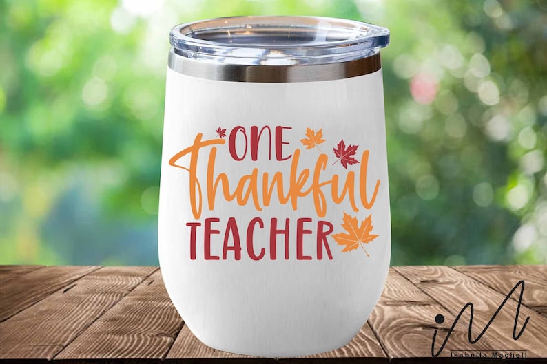 May include: White stainless steel wine tumbler with a red and orange design that says "One Thankful Teacher" with fall leaves.