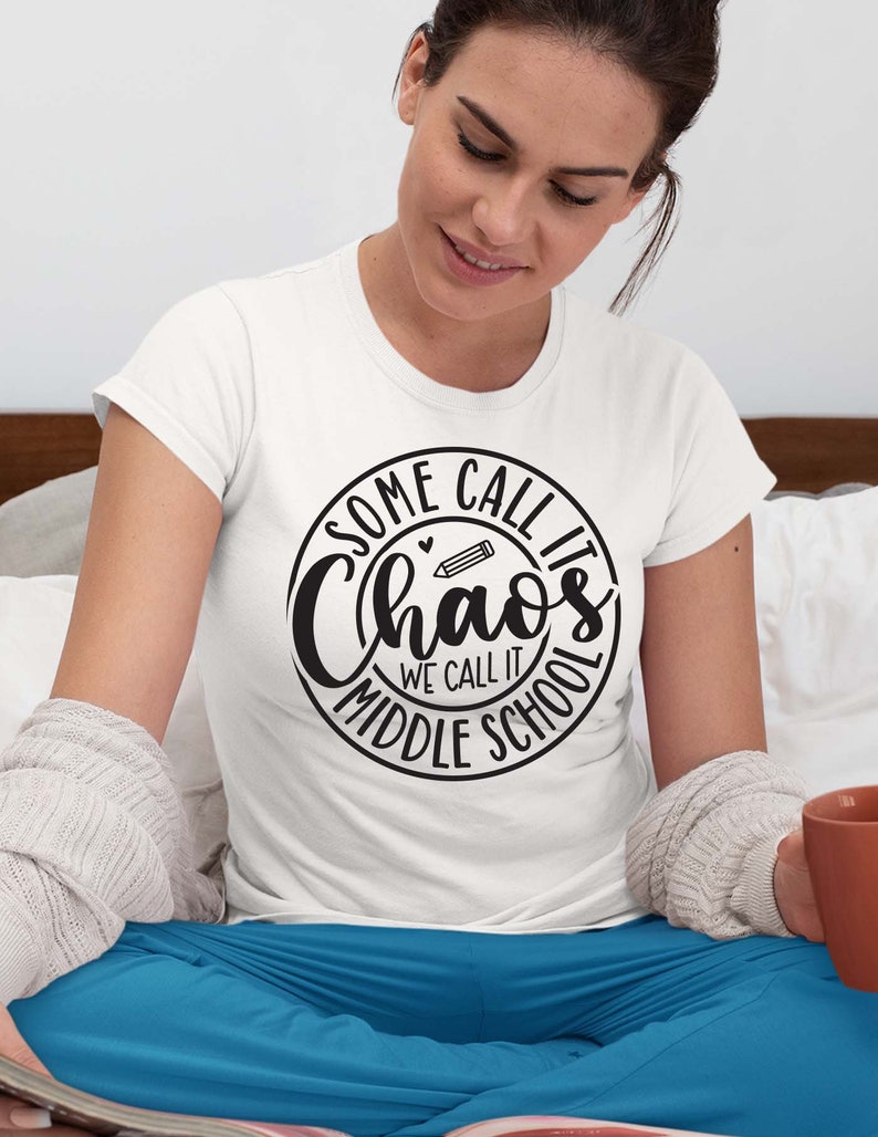 Puede incluir: Camiseta blanca con un gr&aacute;fico circular negro que dice "Some call it chaos we call it middle school" con un l&aacute;piz y un coraz&oacute;n dentro del c&iacute;rculo.