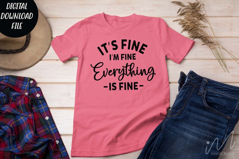 May include: A pink short-sleeved t-shirt featuring black text that reads IT'S FINE I'M FINE Everything -IS FINE- centered on the front. The shirt is displayed alongside a brown hat, a plaid flannel shirt, and a pair of dark blue denim jeans.