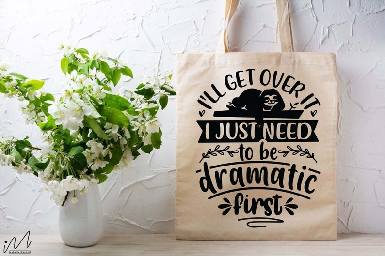 May include: A beige tote bag with a black graphic of a sloth and the text "I'll get over it I just need to be dramatic first".