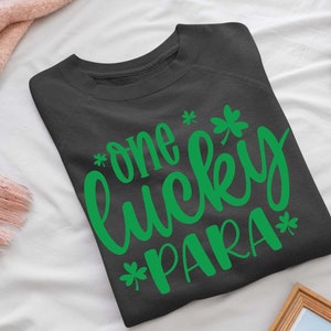 May include: A dark gray sweatshirt with the text "*one lucky PARA*" in green lettering. The text is in a cursive font and includes shamrock symbols.