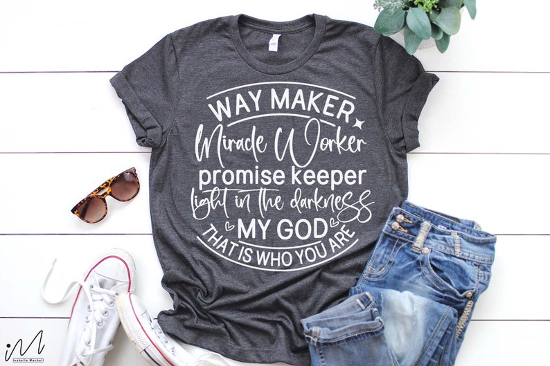 May include: A dark gray t-shirt with a white circle design that says "Way Maker Miracle Worker Promise Keeper Light in the Darkness That is Who You Are My God".
