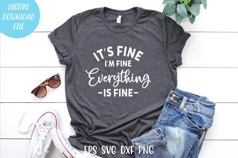 May include: A dark heather gray short-sleeve t-shirt featuring the white text IT'S FINE I'M FINE Everything -IS FINE- printed on the front. The shirt is displayed alongside a pair of blue denim jeans, white canvas sneakers, and tortoiseshell sunglasses.