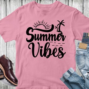Peut inclure: T-shirt rose avec un graphisme noir qui dit "Summer Vibes" avec un soleil et des palmiers.