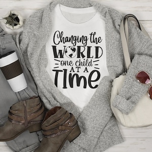 May include: White t-shirt with the text "Changing the WORLD one child at a TIME" and a small globe graphic.