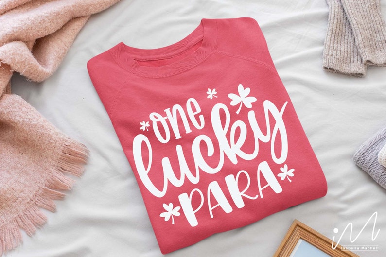 May include: A pink sweatshirt with the text "one lucky para" in white lettering with shamrock designs.