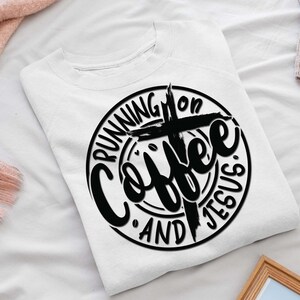 May include: White sweatshirt with a black circle design that says "Running on Coffee and Jesus" with a cross in the center.