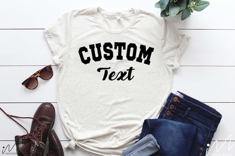 May include: A white t-shirt with a black graphic that says "CUSTOM Text" in a collegiate font.