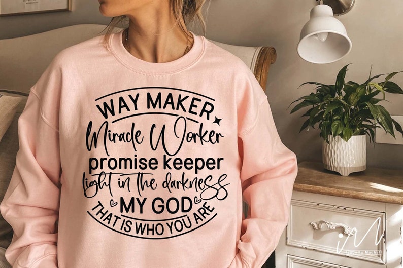 May include: Pink sweatshirt with a black circle graphic that says "Way Maker, Miracle Worker, Promise Keeper, Light in the Darkness, My God, That is Who You Are."